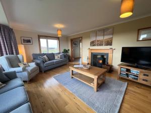 a living room with a couch and a table and a tv at Airigh nam Fiadh in Carnan