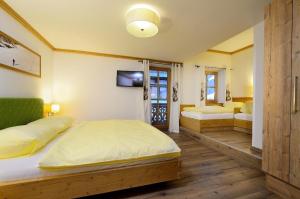 Un dormitorio con dos camas y un televisor en la pared. en Bachgut, das Resort am Berg - Stammhaus Winter, en Saalbach Hinterglemm
