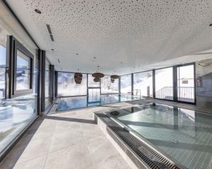 una piscina en una casa con ventanas de cristal en Bachgut, das Resort am Berg - Stammhaus Winter, en Saalbach Hinterglemm