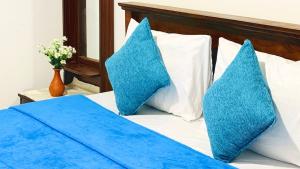 a bed with two blue pillows on it at Vilona Inn in Dehintalawa