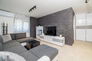 a living room with a gray couch and a brick wall at Apartment Slavko in Mundanije