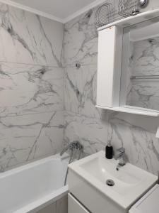a white bathroom with a sink and a white tub at LCB Apartments Universitate Suceava A59 in Suceava