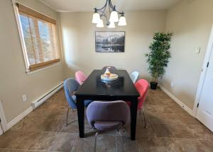 a dining room with a black table and pink chairs at The Family Hub-Moncton Central-NBCC-Casino NB in Moncton