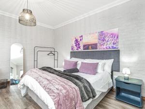 a white bedroom with a large bed with purple pillows at Links & Lavender in Centurion