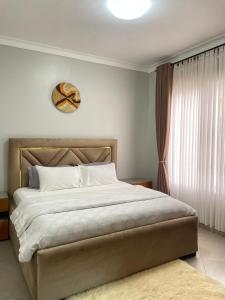 1 dormitorio con 1 cama grande y reloj en la pared en TraveltonHomes, en Kampala