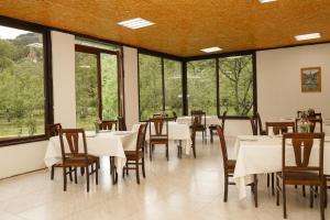 a dining room with white tables and chairs and windows at Restland Dilijan Family Hotel in Dilijan