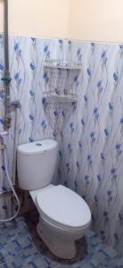 a bathroom with a toilet and blue and white wallpaper at Oseng Pesona House in Ketapang