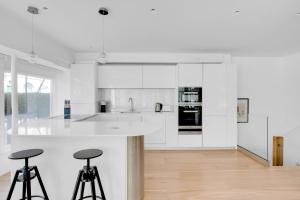 a white kitchen with a counter and stools at Blueground Fitzrovia spa nr Oxford St LON-178 in London
