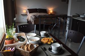 una mesa con alimentos para el desayuno en ella con una cama en El Chalten Aparts en El Chaltén
