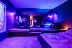 a bedroom with purple lighting and a bed and a tv at Jacuzzi Cinema Wabi Sabi 3 in Kaunas