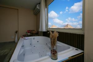 Una bañera con un jarrón delante de una ventana. en pyramids palace view, en El Cairo