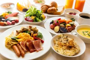 a table with plates of breakfast foods and drinks at Hotel Resol Sapporo Nakajima Koen in Sapporo