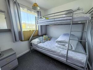 a bedroom with two bunk beds and a window at Stunning Chalet In The Charming Seaside Village Of Scratby, Norfolk Ref 51017S in Great Yarmouth