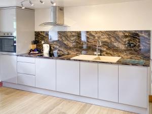 a kitchen with white cabinets and a sink at The Milking Parlour in Alston