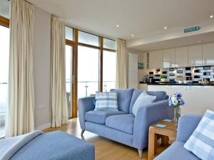 Una sala de estar con un sofá azul y una mesa. en Pebbles, Horizon View, en Westward Ho