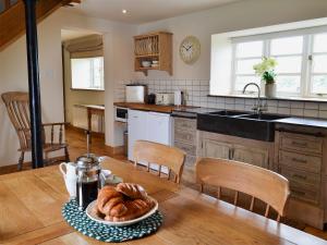 a kitchen with a table with a plate of bread at Mullins Cottage in Gristhorpe