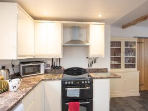 a kitchen with white cabinets and a stove top oven at Top House in Forden +16 photos