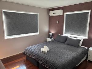 a bedroom with two windows and a bed with a stuffed animal on it at Family retreat near Caboolture Hospital in Caboolture +21 photos