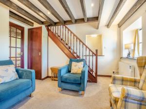ein Wohnzimmer mit zwei blauen Stühlen und einer Treppe in der Unterkunft Black Bull Cottage in Ugthorpe