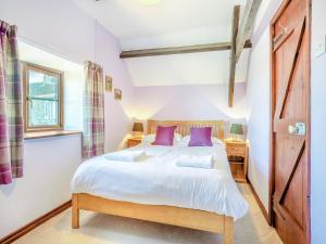 ein Schlafzimmer mit einem großen weißen Bett mit lila Kissen in der Unterkunft Black Bull Cottage in Ugthorpe + 14 Fotos