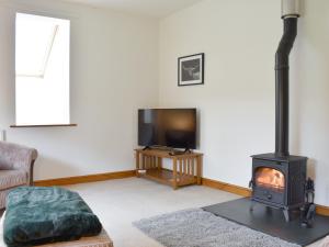 a living room with a wood stove and a tv at Quarry Cottage in Penrith