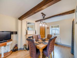 a dining room with a table and chairs and a tv at Barbers Bolthole in Masham