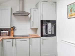 a kitchen with white cabinets and black appliances at The Barn in Llangwm