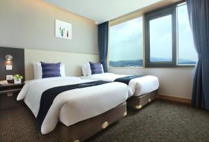 two beds in a hotel room with large windows at Hotel Skypark Kingstown Dongdaemun in Seoul
