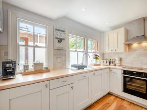 una cocina blanca con armarios blancos y ventanas en Stradbroke House, en Cromer 22 fotos más
