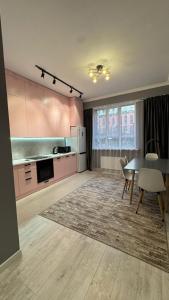 a kitchen with pink cabinets and a table with chairs at Luxury & City Central Apartment & Great Atmosphere in Almaty +31 photos