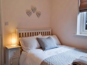 ein Schlafzimmer mit einem Bett mit einem blauen Kissen und einer Lampe in der Unterkunft Cottage On The Green in York