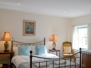 a bedroom with a bed and a chair and a window at Temple House West in Drumnadrochit