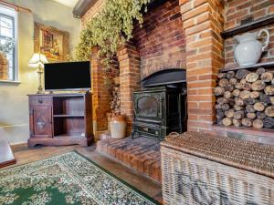 a living room with a brick fireplace and a television at The Cottage in East Bergholt