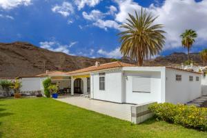 a white house with a deck and a palm tree at 3BR Tauro Bungalow - Garden, Terrace, Sleeps 6 in Mogán