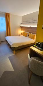 a bedroom with a large bed and a chair at Hôtel des Halles in Dijon