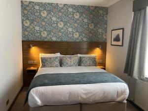 a bedroom with a large bed with a wooden headboard at The Abbey Inn in Paisley