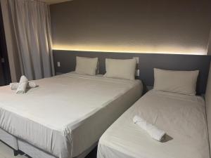 two beds in a room with white sheets and pillows at Saint Patrick Grand Hotel in Maceió