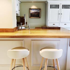 a kitchen with two white stools at a counter at Quite location Near the Quay, Newly Refurbished 2 Ensuite Kingsize Bedrooms in Blakeney
