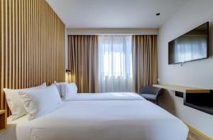 a large white bed in a hotel room at Select Porto in Porto