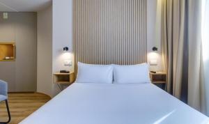 a bedroom with a large white bed and a chair at Select Porto in Porto