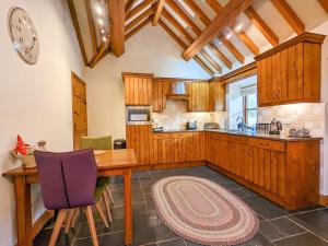 una cocina con armarios de madera, mesa y sillas en Yr Efail - Hw7387, en Llanymawddwy