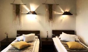 two beds in a bedroom with two lights on the wall at Pensiunea Andreea in Muntele Băişorii