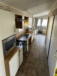 a kitchen with a stove and a tv in it at Coastfield Holiday Village - Holiday Accommodation 4562 in Ingoldmells