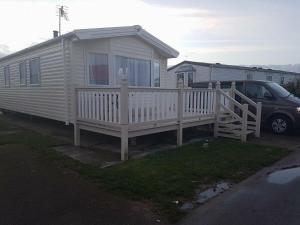 a small white house with a porch and a car at Coastfield Holiday Village - Holiday Accommodation 4562 in Ingoldmells