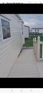 a white house with a porch and a window at Coastfield Holiday Village - Holiday Accommodation 4562 in Ingoldmells