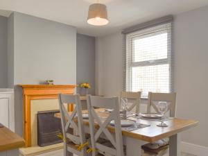 a dining room with a table and chairs and a fireplace at Newstead Cottage in Weymouth