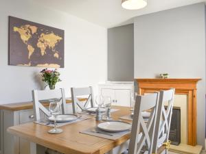 a dining room table with chairs and a world map on the wall at Newstead Cottage in Weymouth