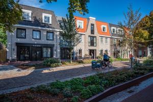 eine Person, die mit einem Fahrrad die Straße hinunter fährt, mit Gebäuden in der Unterkunft Residence Noordstaete vakantieappartement Lepelaar in Burgh Haamstede