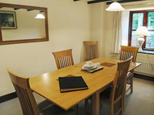 een houten eettafel met stoelen en een spiegel bij Prideaux Cottage in Luxulyan