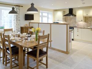 a kitchen and dining room with a wooden table and chairs at Herons Weir in Buckland Dinham